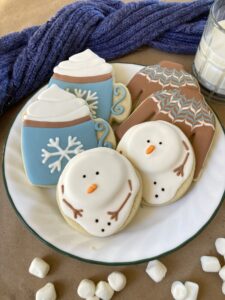 Sugar cookies decorated to look like Sweaters, Hot Cocoa and melted snowmen.